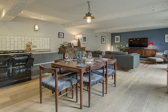 Interior of Dairy Cottage in Chagford - dining table, kitchen with aga and living space with large flat screen TV.