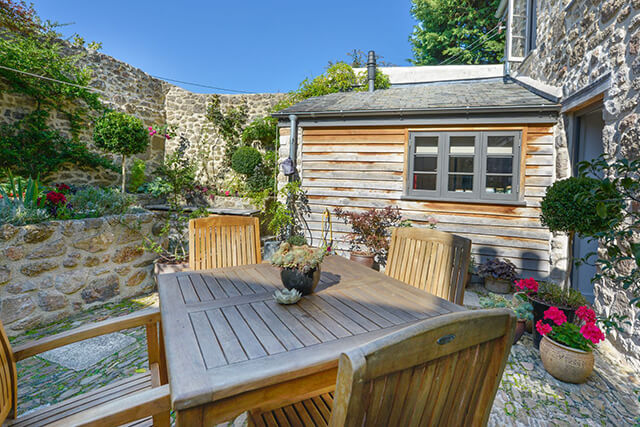 Exterior of Dairy cottage with patio furniture, walled gardens and beautiful flowers.