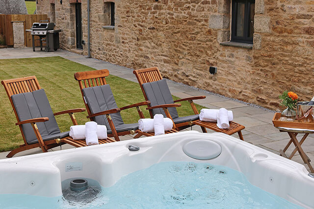 hot tub with lounging chairs, towels and champagne in a garden.