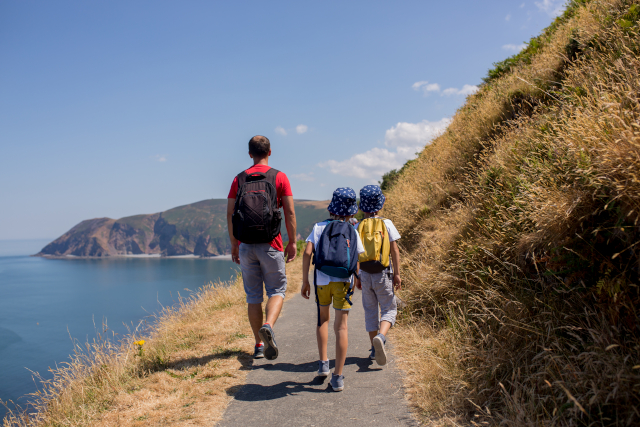 Father and two boys walking along the coast