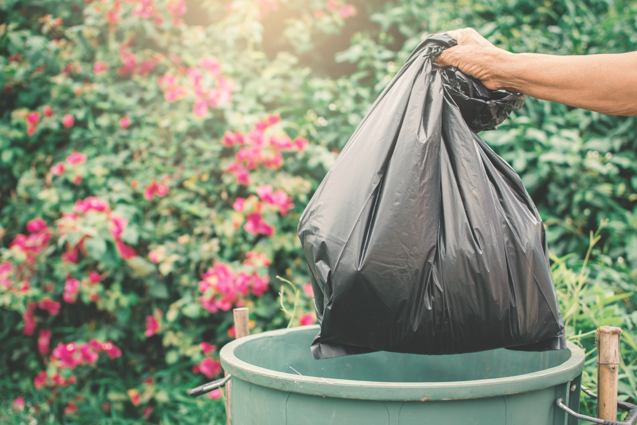 Old hand holding plastic bag in to trash Old hand holding plastic bag in to trash