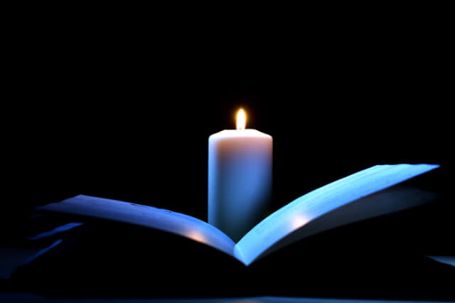 open-book-lit-by-candlelight-in-the-dark