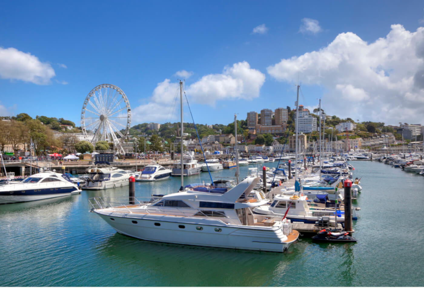 View of Torquay from the harbour with boats in the foreground and the English Riviera Wheel in the background.