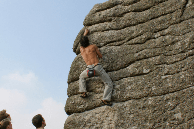 Man tackles boulder problem at Bonehill Rocks in Dartmoor.