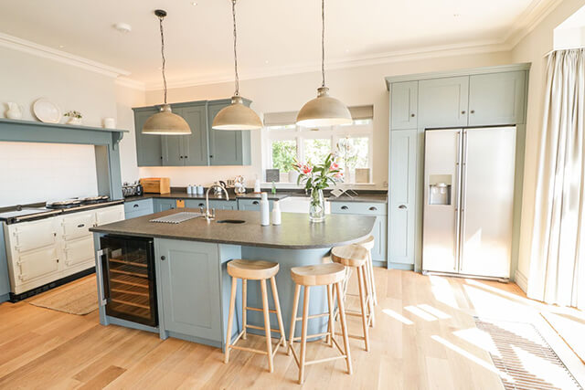 the woods salcombe kitchen, complete with appliances and island with bar stools.