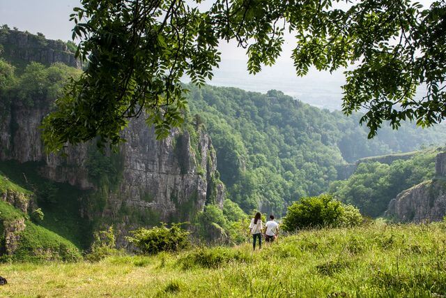 Two people on a walk in the Mendips on the Cheddar Trail, with a view of Cheddar Gorge in the background.