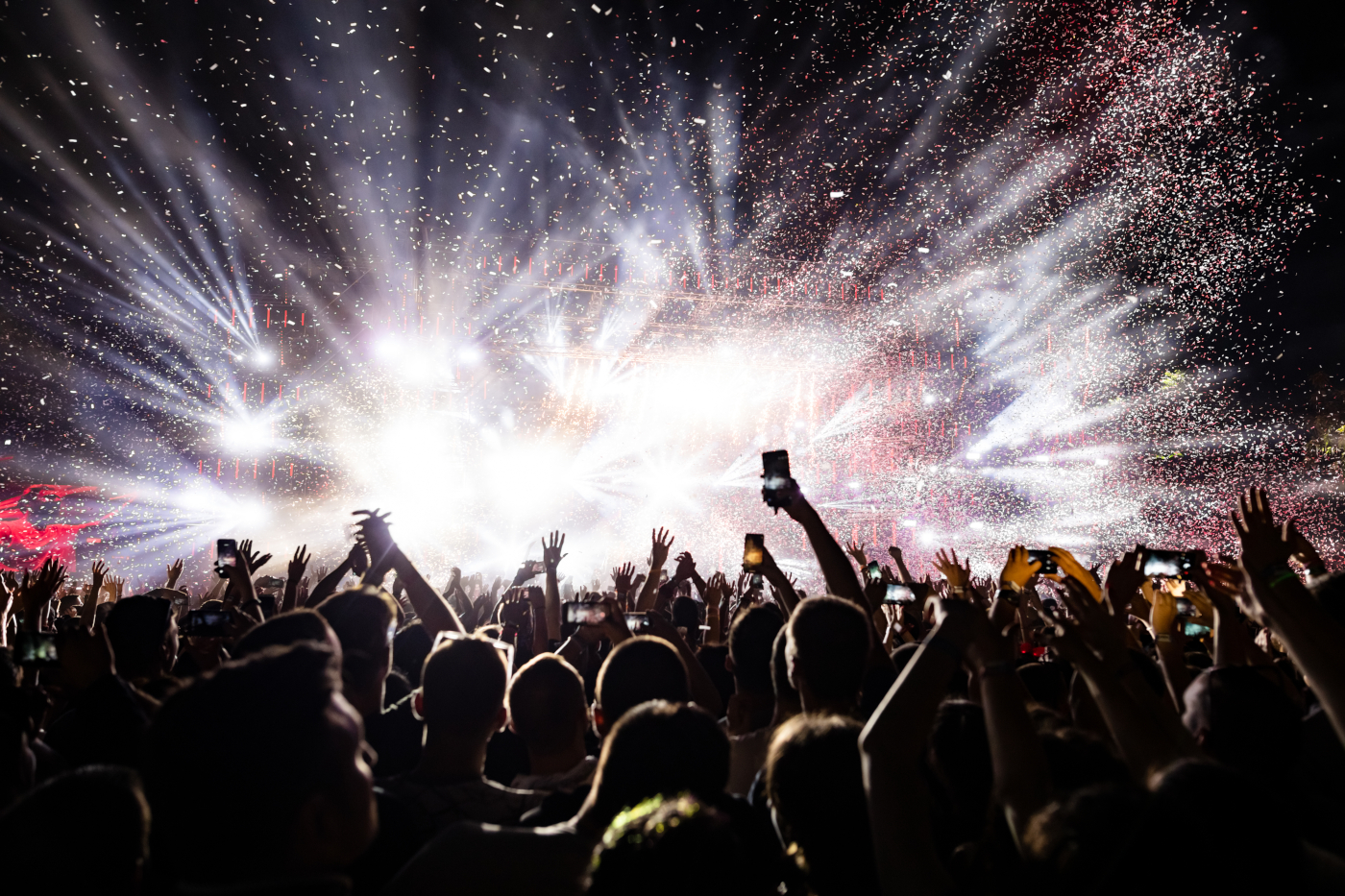 Confetti fireworks above the crowd at a music festival.