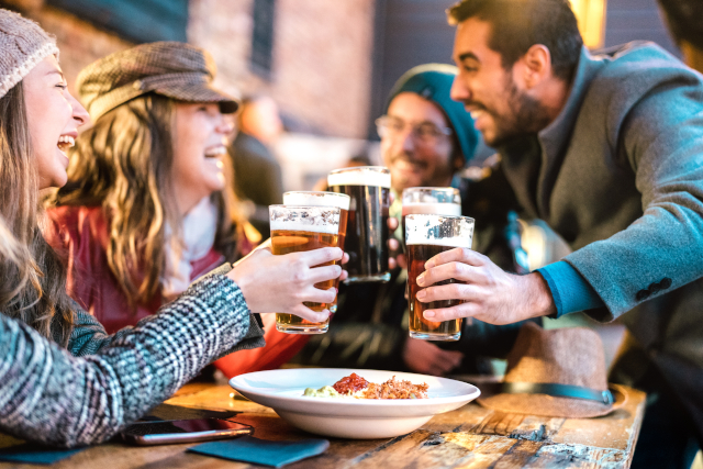 Group of friends toasting pints of beer.