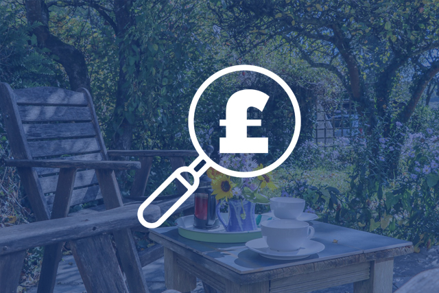 South West Holiday Let Marketing and Advertising Tips: Money and magnifying glass icon overlaid on an image of an outdoor dining area
