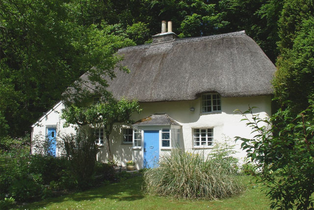 View through trees of the thatched Lew Quarry Cottage, Lewdown