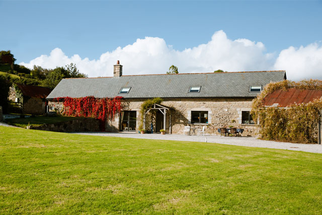 View of Higher Weddicott Barn, Chagford, with a tidy lawn in the foreground.