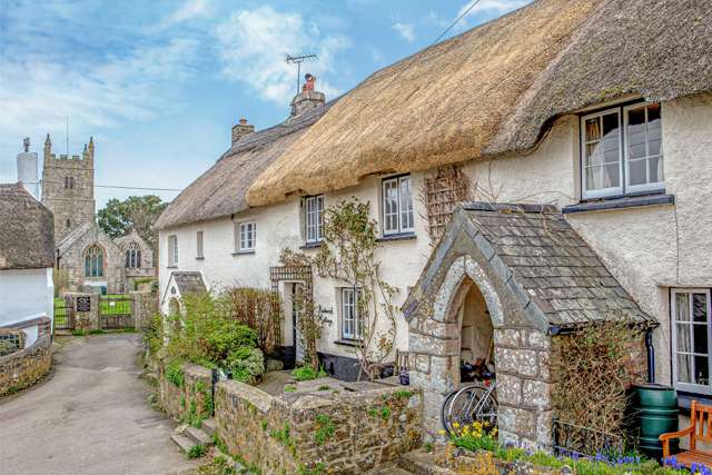 A pretty thatched terraced cottage, facing onto a lane which leads to a village church.