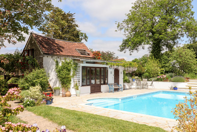 Swimming pool in front of the conservatory at Shillings Cottage, Hemyock, on a sunny day