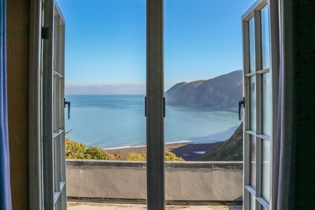 View of sea and cliffs on a sunny day, through french doors