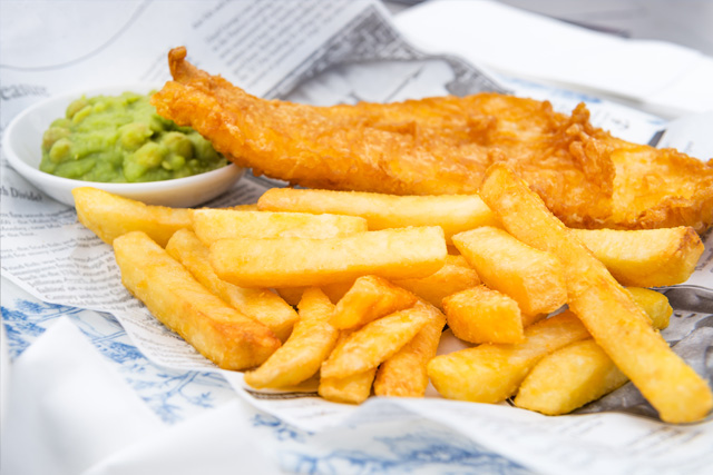Traditional fish and chips, served with mushy peas, on some newspaper.