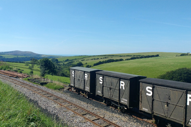 Historic railway carriages on tracks, with a view of Exmoor hills in the background