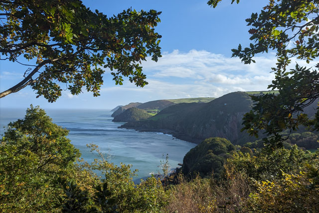 View of Woody Bay, sea and cliffs from the South West Coast Path, on a sunny day.